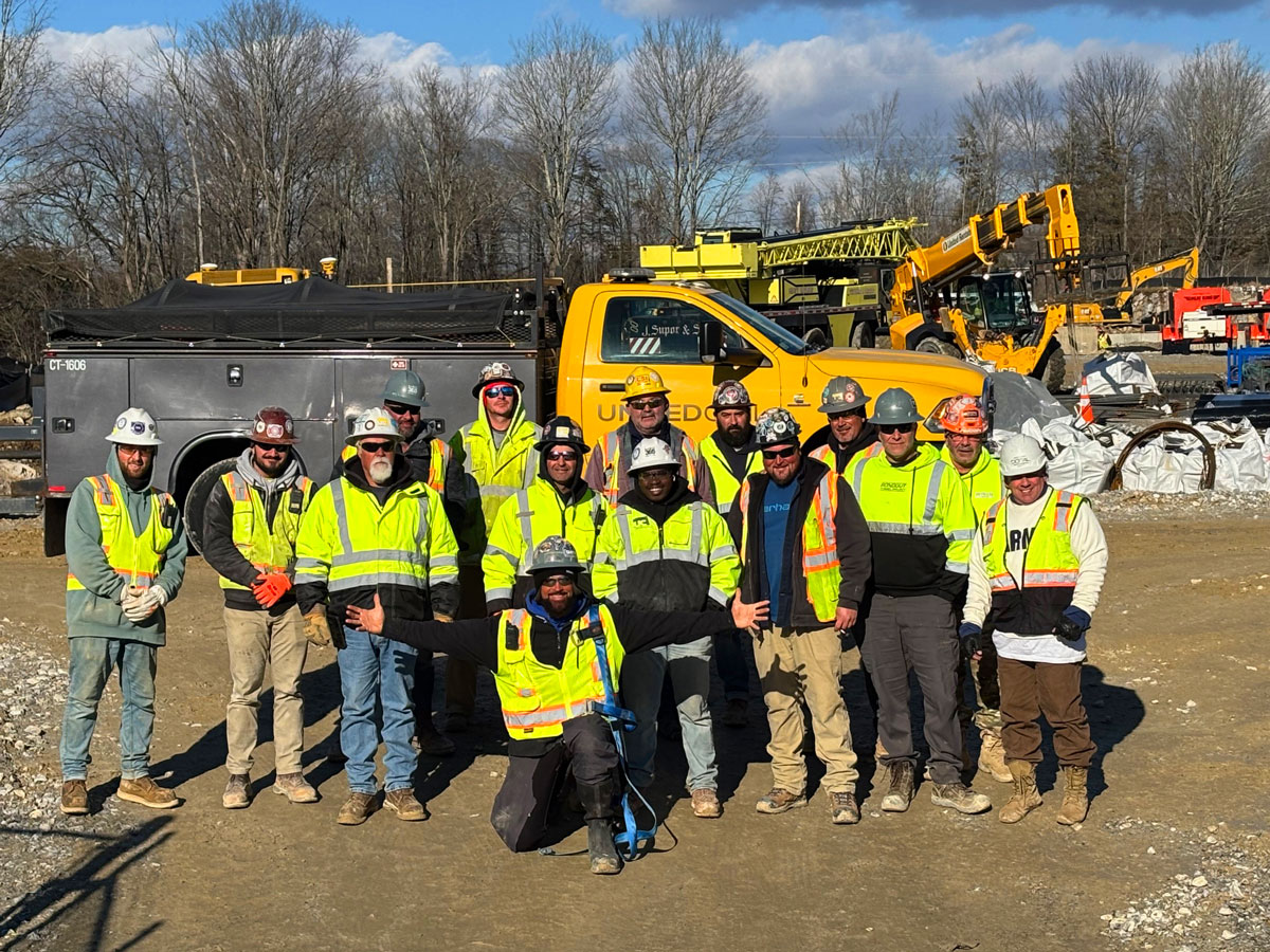 United Civil field crew posing together in hardhats and hi-vis vests at an outdoor utility construction jobsite