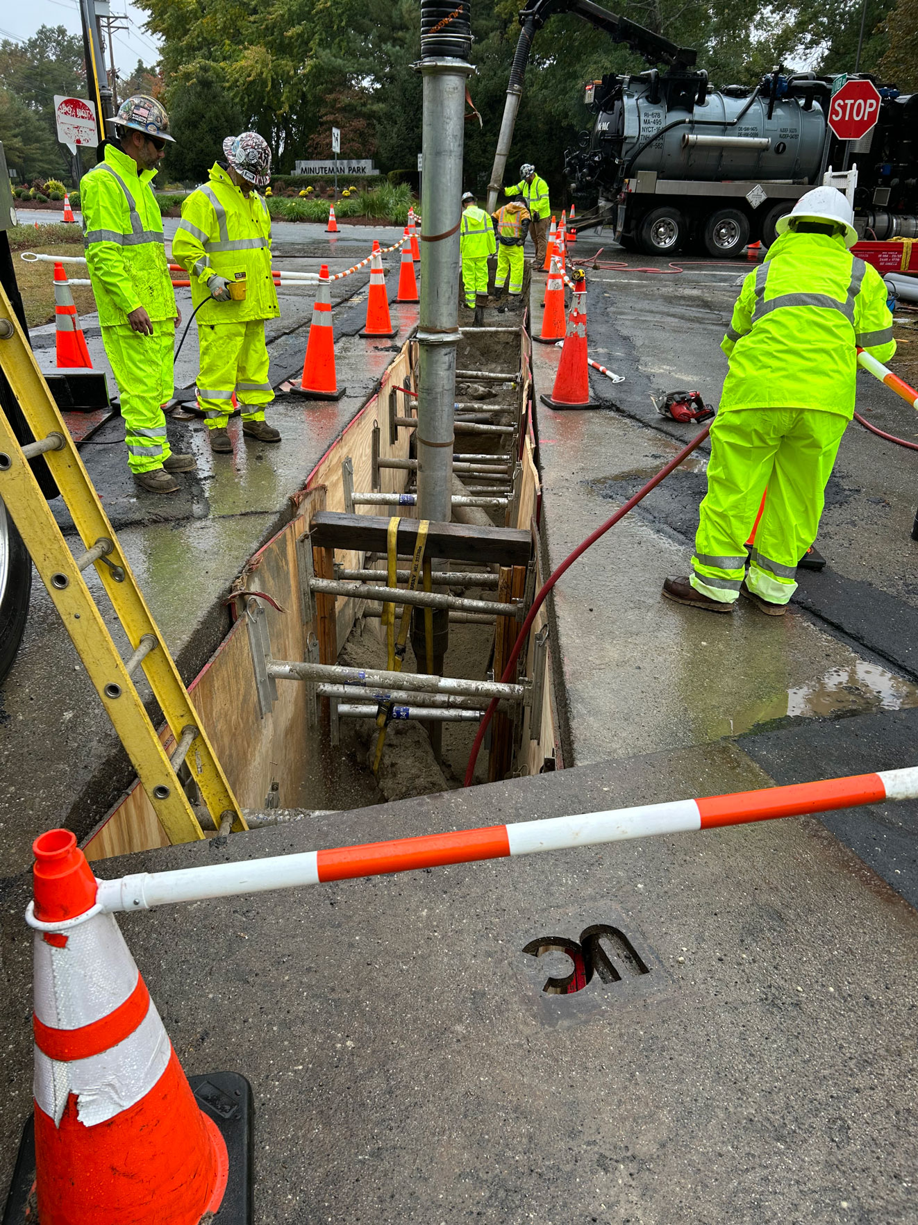 United Civil workers in hi-vis vests performing electrical distribution vault installation in an urban work zone