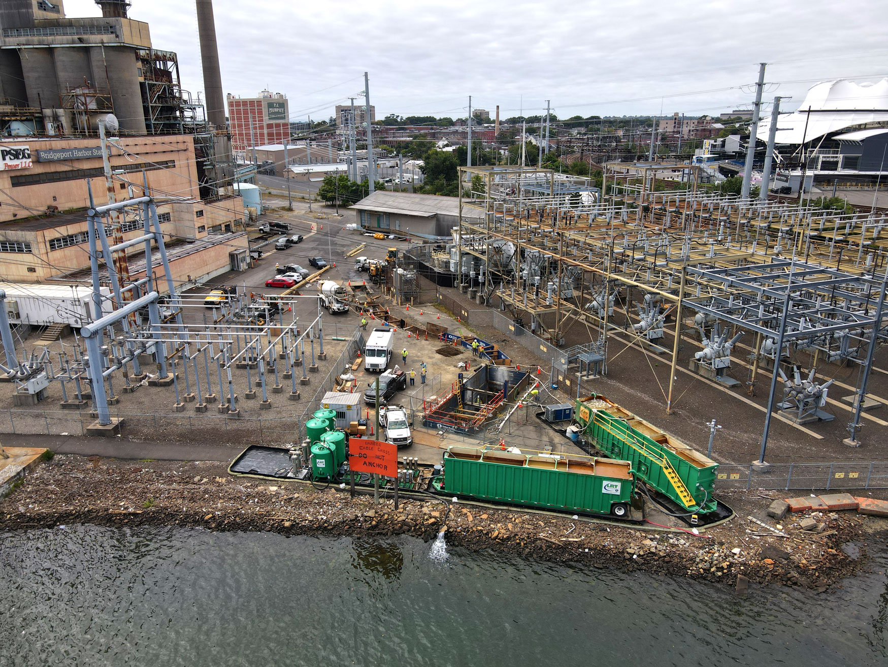 Aerial view of a United Civil energy infrastructure construction project near a waterfront industrial area