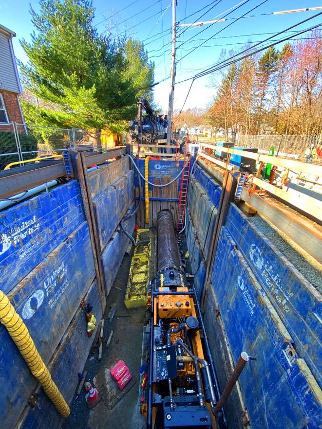 United Civil crew working inside a deeply shored trench with blue steel shoring panels during a specialty underground installation