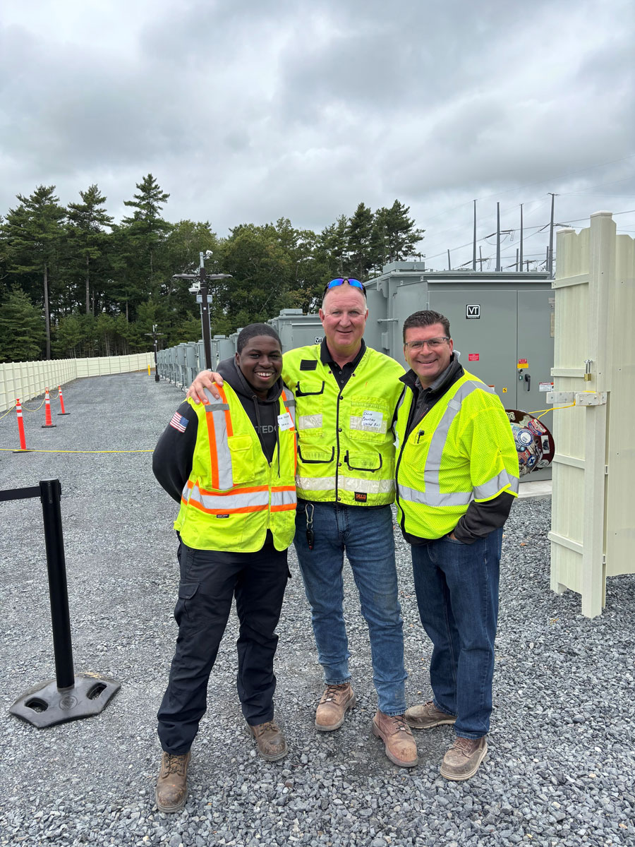Three United Civil team members posing together in hi-vis vests at an outdoor utility construction jobsite