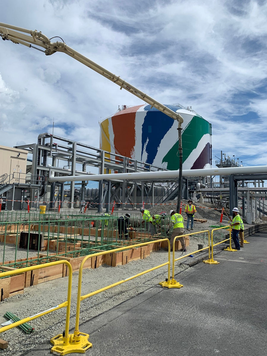 United Civil safety-trained workers in high-visibility vests and hard hats working on a concrete foundation reinforcement project at an industrial facility.